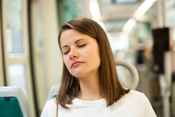 Portrait of young woman going to work by bus or trolley at early morning sitting with closed eyes