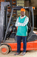 Portrait of afro man posing near stacker in warehouse with mandarins