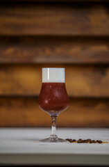 Crushed ice coffee with cinamon in brandy glass on table with wood background and coffee beans