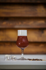 Crushed ice coffee with cinamon in brandy glass on table with wood background and coffee beans
