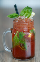 Fresh pomegranate lemonade detail with crushed ice and mint and straw on table with wood background
