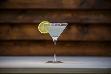Fresh cold martini cocktail glazed and crushed ice with lime garnish on table with wood background
