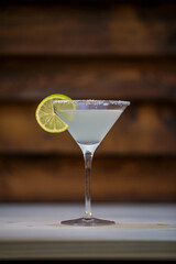 Fresh cold martini cocktail glazed and crushed ice with lime garnish on table with wood background