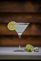 Fresh cold martini cocktail glazed and crushed ice with lime garnish on table with wood background