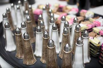 A view of several salt and pepper dispensers, seen during prep of a local restaurant.