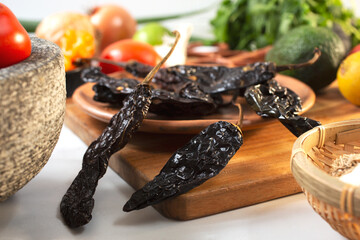 A view of a pile of dried chile negro, among other salsa ingredients.