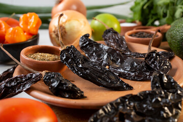 A closeup view of a pile of dried chile negro, among other salsa ingredients.