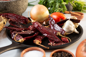 A view of guajillo chiles on a comal, among other salsa ingredients.