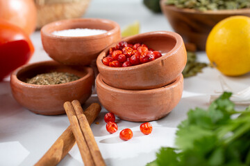 A view of a clay condiment cup full of tepin chiles, among other Mexican ingredients.