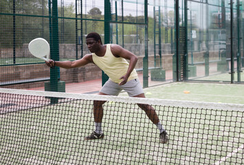African american man playing paddle tennis on the padel court