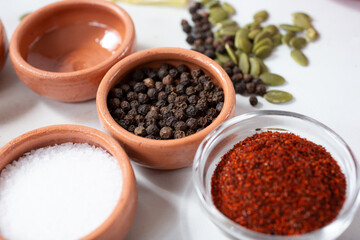 A view of a condiment cup of black peppercorn, among other seeds and spices.