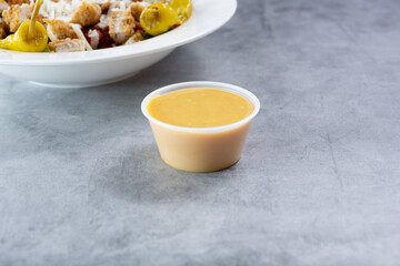 A view of a condiment cup filled with either Italian dressing or honey mustard dressing.