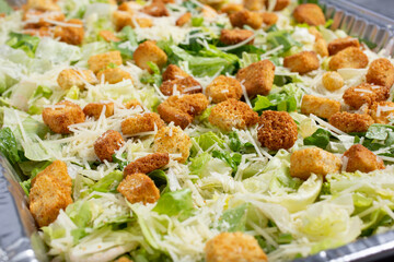 A view of a catering size tray filled with Caesar salad.