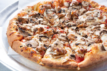 A view of a pizza pie, featuring toppings as sausage and mushrooms.