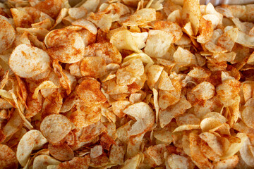A top down view of a pile of seasoned potato chips, as a background.
