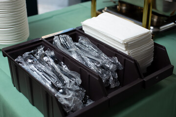 A view of a compartment for individually wrapped cutlery sets and paper napkins, seen in a catering event.