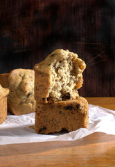Banana muffins with a slice of butter with dark and white background on a wooden table