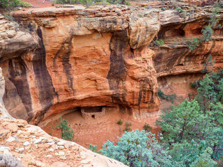 Small cliff dwelling under black-streaked high cliff