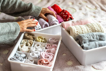 Top view mother hands neatly putting female kid clothes into plastic case box comfortable storage