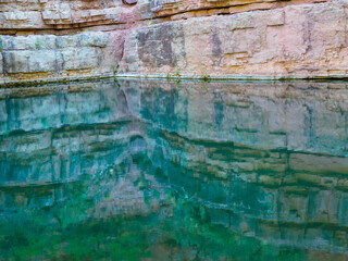 Reflection of a limestone cliff in quiet water