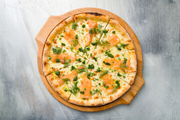 Pizza with salmon, cheese and green onion on the board on grey table top view