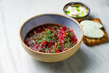 Borscht with sour cream on grey table side view