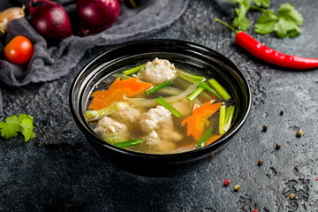 Chicken soup with chicken meatballs and vegetables on black bowl, Chinese cuisine