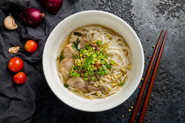 Soup Pho Bo with beef and noodles on white bowl on dark stone table top view