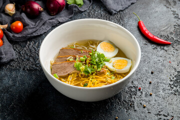 Ramen soup with pork on white bowl on dark stone table