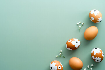 Elegant Easter flat lay composition. Painted Easter eggs and gypsophila on green background. Top view with copy space. Happy Easter concept. Minimal style.
