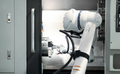 Modern factory. Robot feed workpiece on CNC lathe machine. Industrial manufacturing.