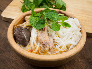 Thai vermicelli eaten with curry and vegetable in wooden bowl on old wood table background. noodle