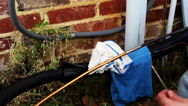 Maintenance worked uses and oxygen Acetylene torch to braze copper tubing on an air conditioner system