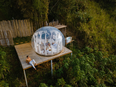 Bubble dome tent glamping in the mountains of Chiang Mai Thailand, Transparent bell tent with comfortable bed and pillow in the forest, glamping hotel, luxury travel, glamourous camping. 