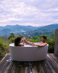 Bathtub during sunset in the mountains of Chiang Mai Thailand, relaxing in outdoor wood fire hot tub out in the wilderness. relaxing bath, couple man and woman in bathtub