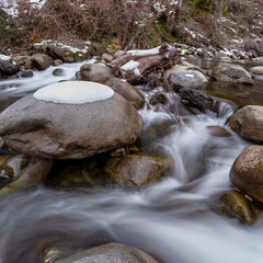 A scenic landscape of a mountain creek covered in snow in the Sierra Nevada Mountains of Northern California.