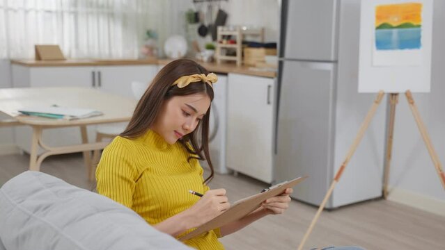 Asian woman artist drawing picture on painting board in living room. 