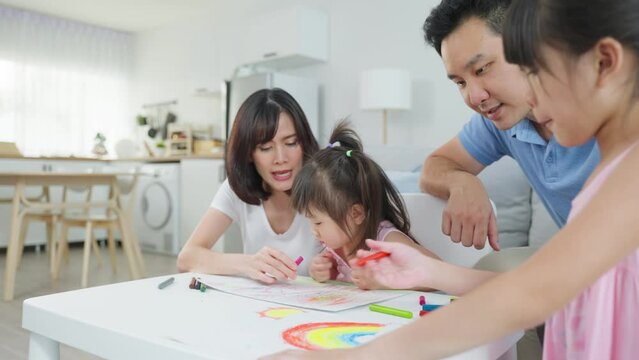 Asian young kid daughter coloring and painting on paper with parents. 