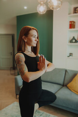 young woman with bright red hair does yoga in stylish modern apartment. woman slender muscular body . yoga basic asanas. home independent training. selective focus, vertically