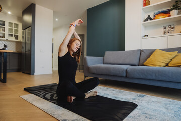 young woman with bright red hair does yoga in stylish modern apartment. woman slender muscular body . yoga basic asanas. home independent training. selective focus, vertically
