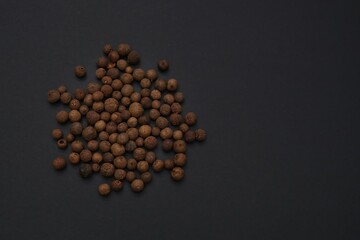 Pile of dried ripe pepper berries allspice pepper peas close-up on a black background. Organic kosher hand selected jamaican allspice on black background. Exotic Pimento Peppercorns