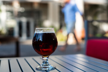  A fresh cold beer has been delivered to a table outside on the street where a pedestrian can be seen in the background though deliberately out of focus to draw the eye to the beverage