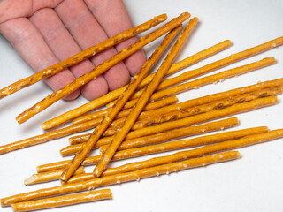 Salted sticks in the hand. Confectionery on the table. Salty baked goods.