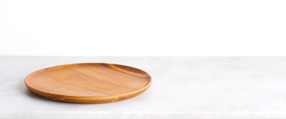 Empty round wooden plate on white cement table and brown cement wall background, Blank wood tray...