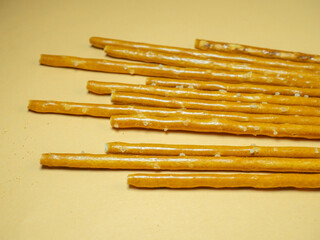 Salted sticks. Confectionery on the table. Salty baked goods. Snack for beer. Dough product on a beige background.
