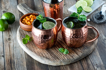 Frosty Moscow Mule cocktails on a rustic wooden board served with peanuts. 
