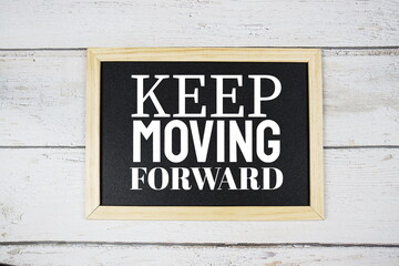 Keep Moving Forward word on blackboard on wooden background