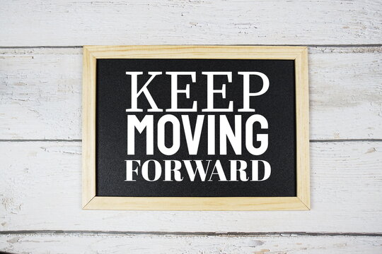 Keep Moving Forward word on blackboard on wooden background