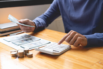 saving concept the guy in the dark blue sweater working on counting cashes and coins that he has...