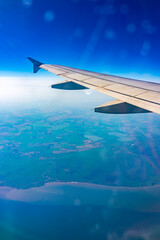 Fototapeta na wymiar View from the airplane window at a beautiful blue clear sky, earth, sea and the airplane wing